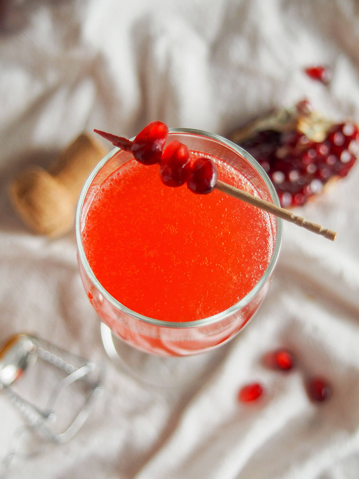 overhead view of cocktail with pomegranate seeds on stick as garnish