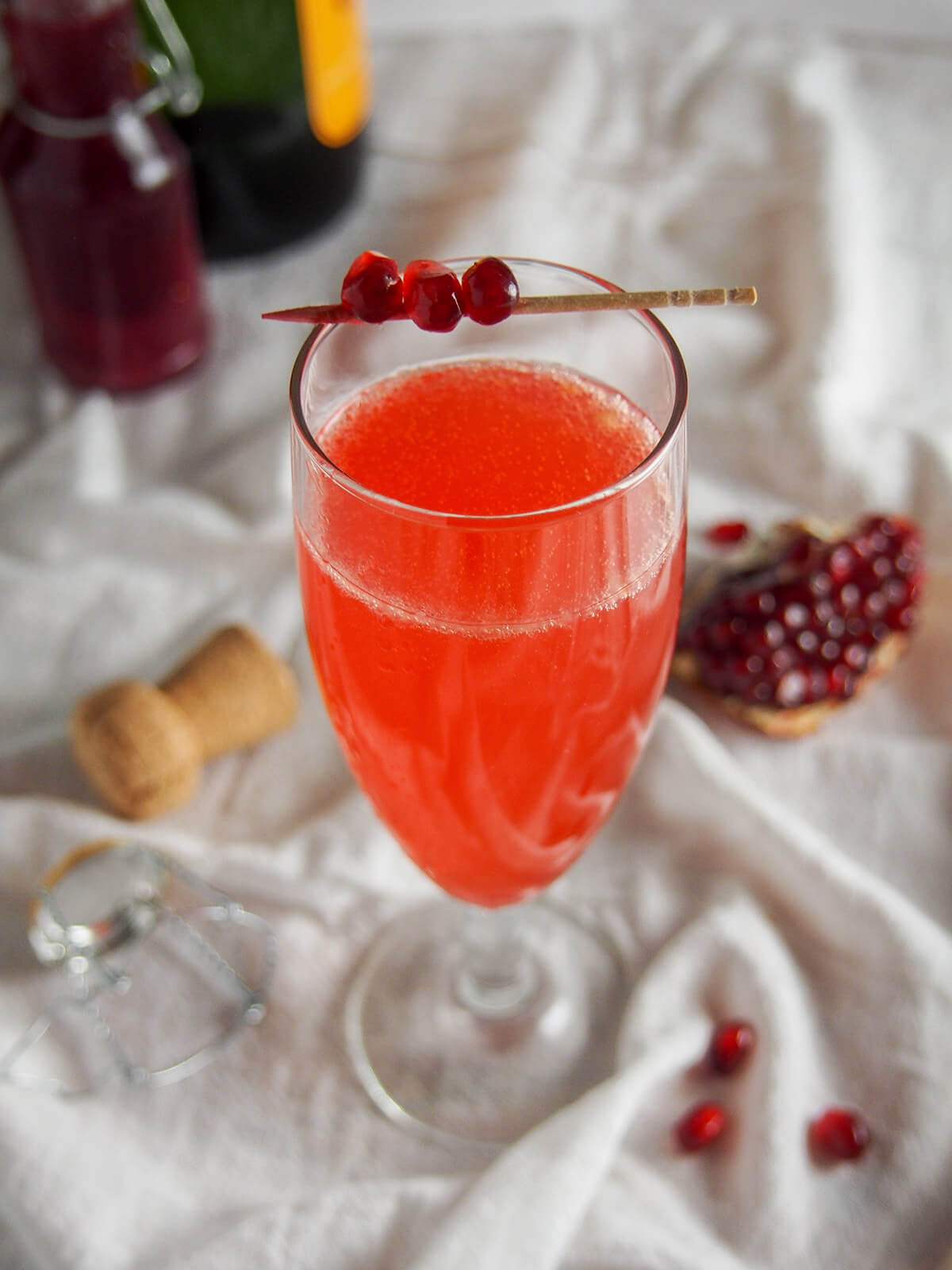 glass of pomegranate French 75 with bottles behind