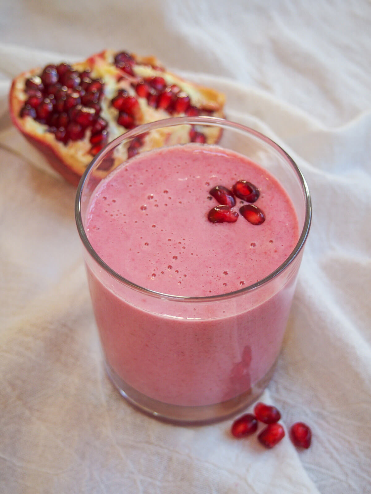 glass of pomegranate smoothie topped with pomegranate seeds