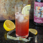 glass of sloe gin fizz with bottle to side behind