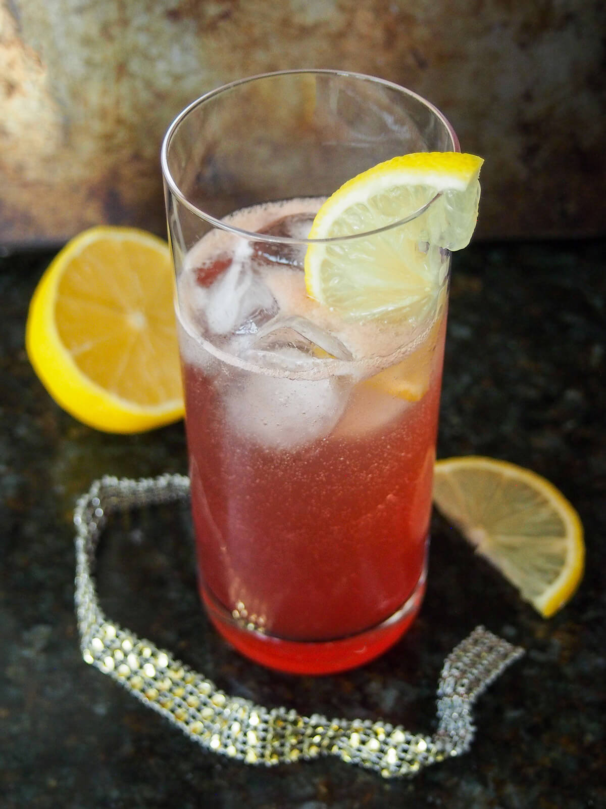 glass of sloe gin fizz with lemon either side