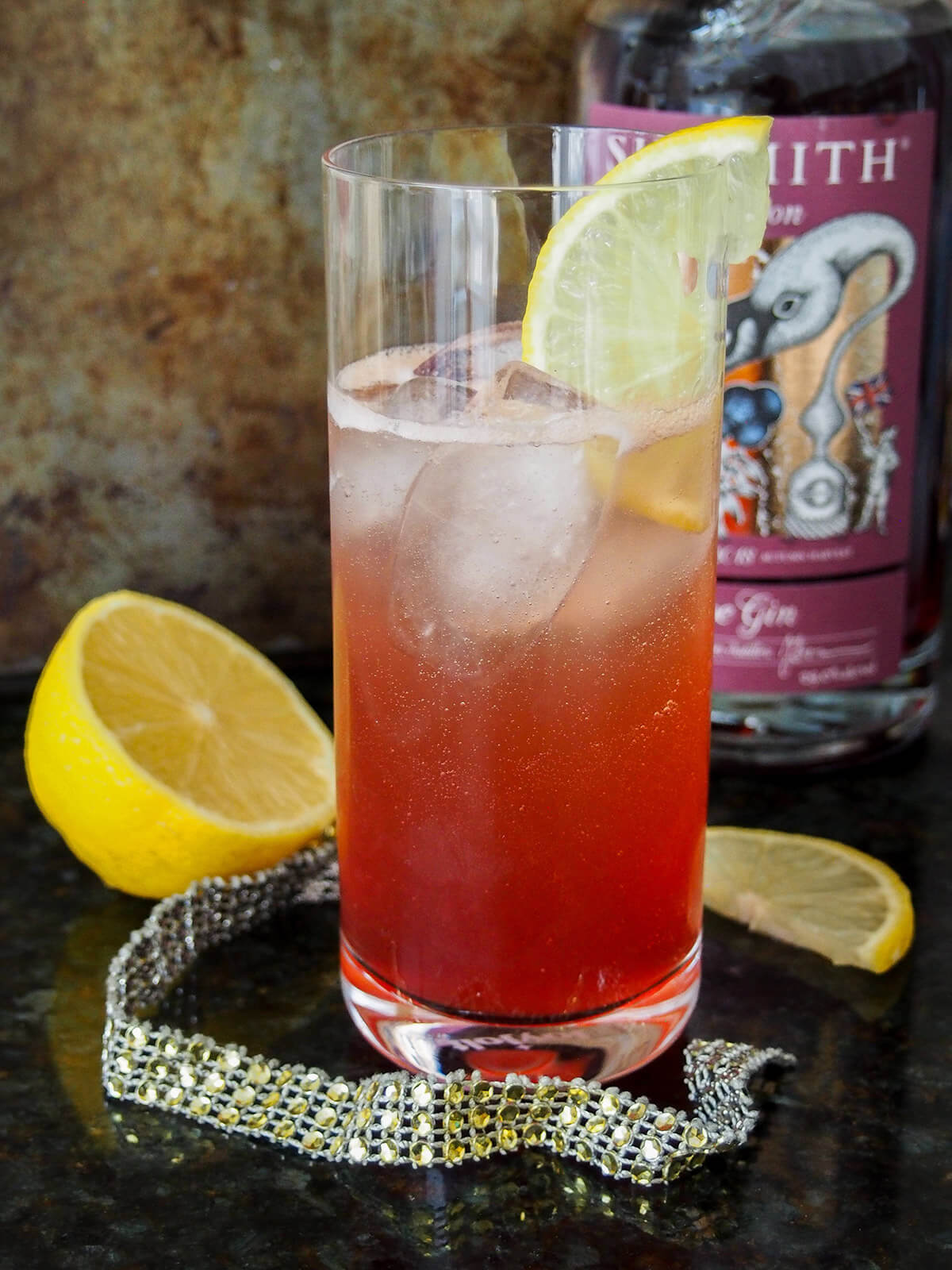 glass of sloe gin fizz with bottle behind