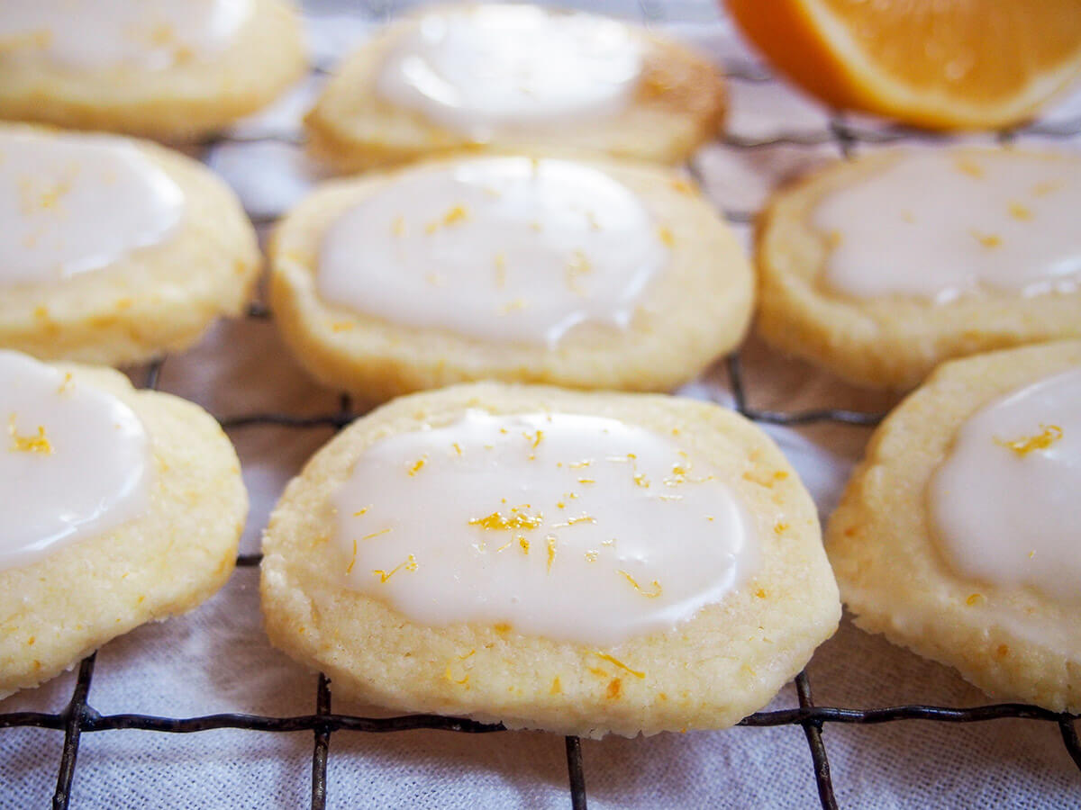 Meyer lemon cookies on cooling rack with part lemon showing behind
