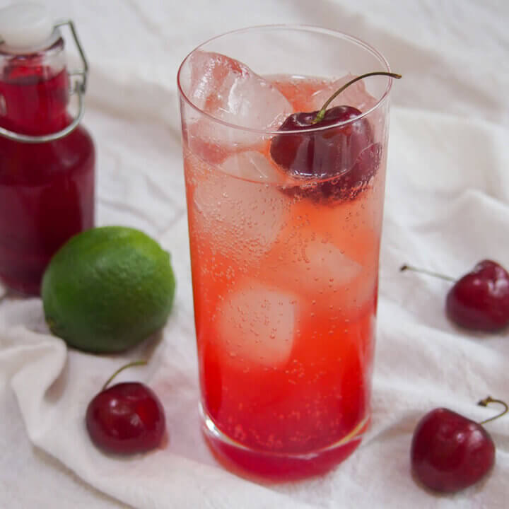 glass of Shirley temple with cherries and lime to side