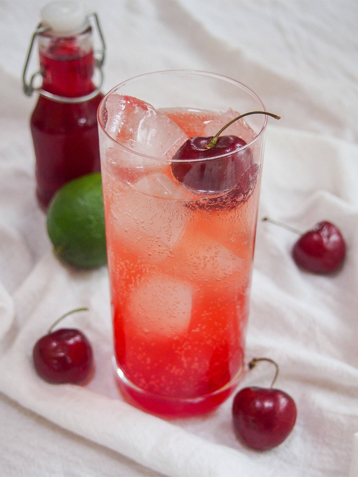 glass of Shirley Temple drink garnished with a cherry on top and cherries to side