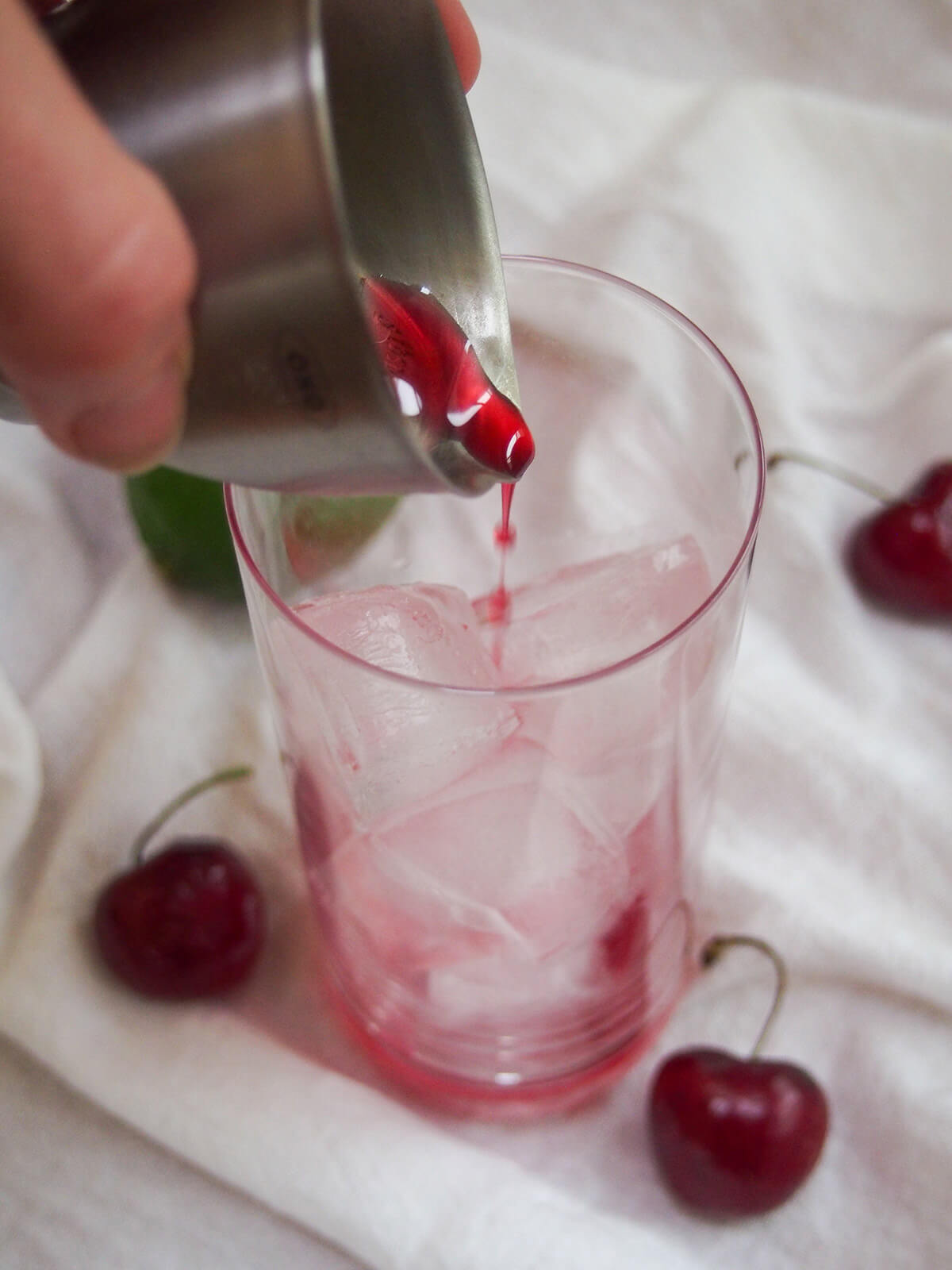 pouring grenadine into glass with ice