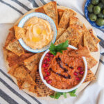 baked pita chips around two small bowls of dips