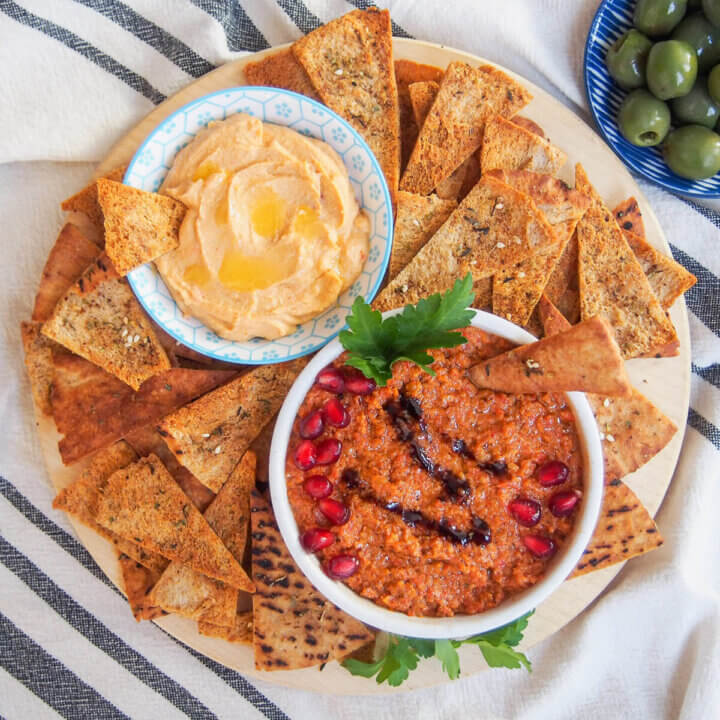 baked pita chips around two small bowls of dips