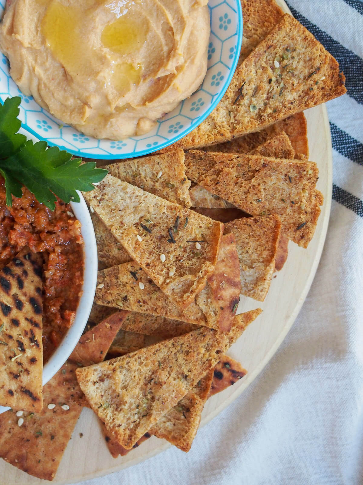 stacked baked pita chips with dips to side