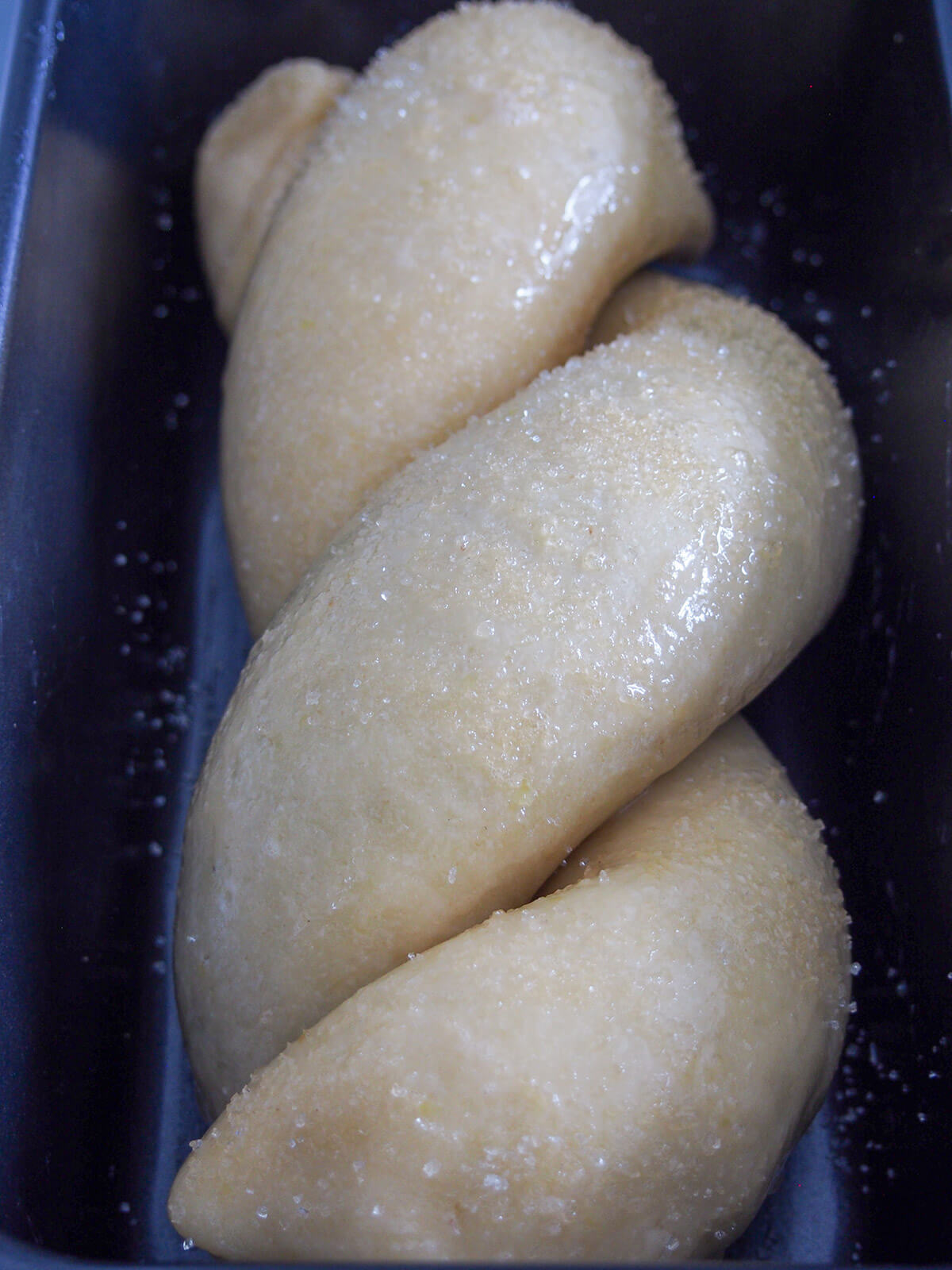 twists of cozonac dough brushed with egg and sugar sprinkled on top before baking