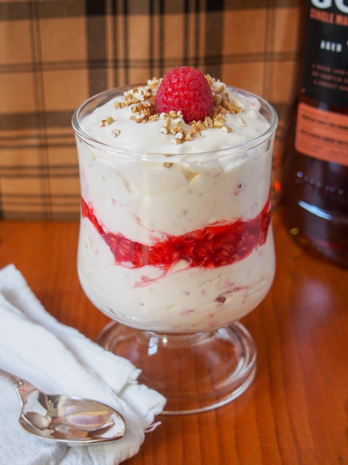 glass with cranachan with a layer of raspberries in the middle