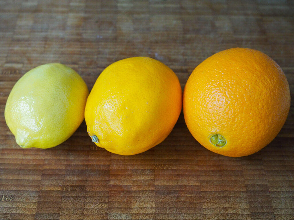 lemon, Meyer lemon and orange in row on wooden board