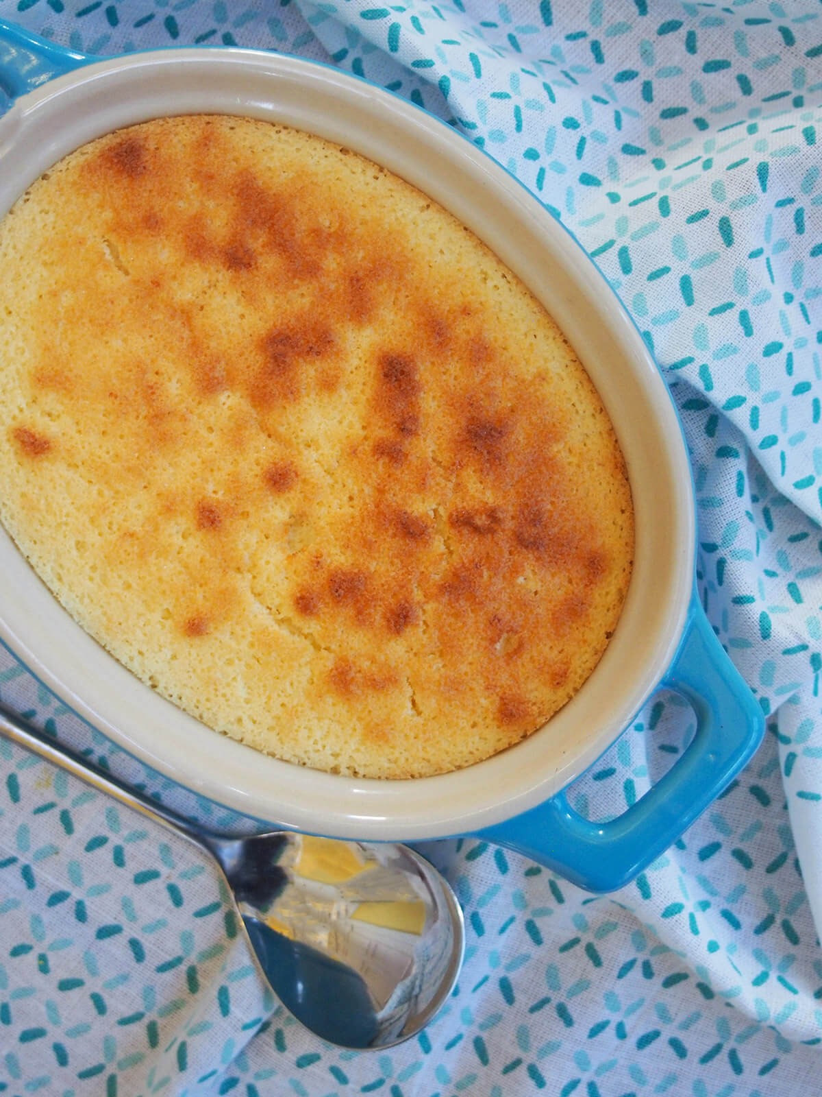 whole lemon pudding cake in baking dish with spoon below