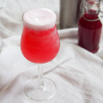 glass of pink gin fizz with foamy white top
