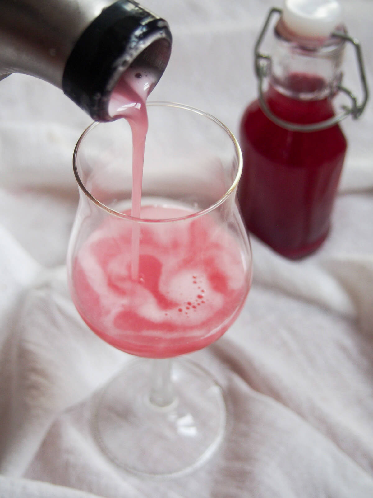 pouring pink drink into glass
