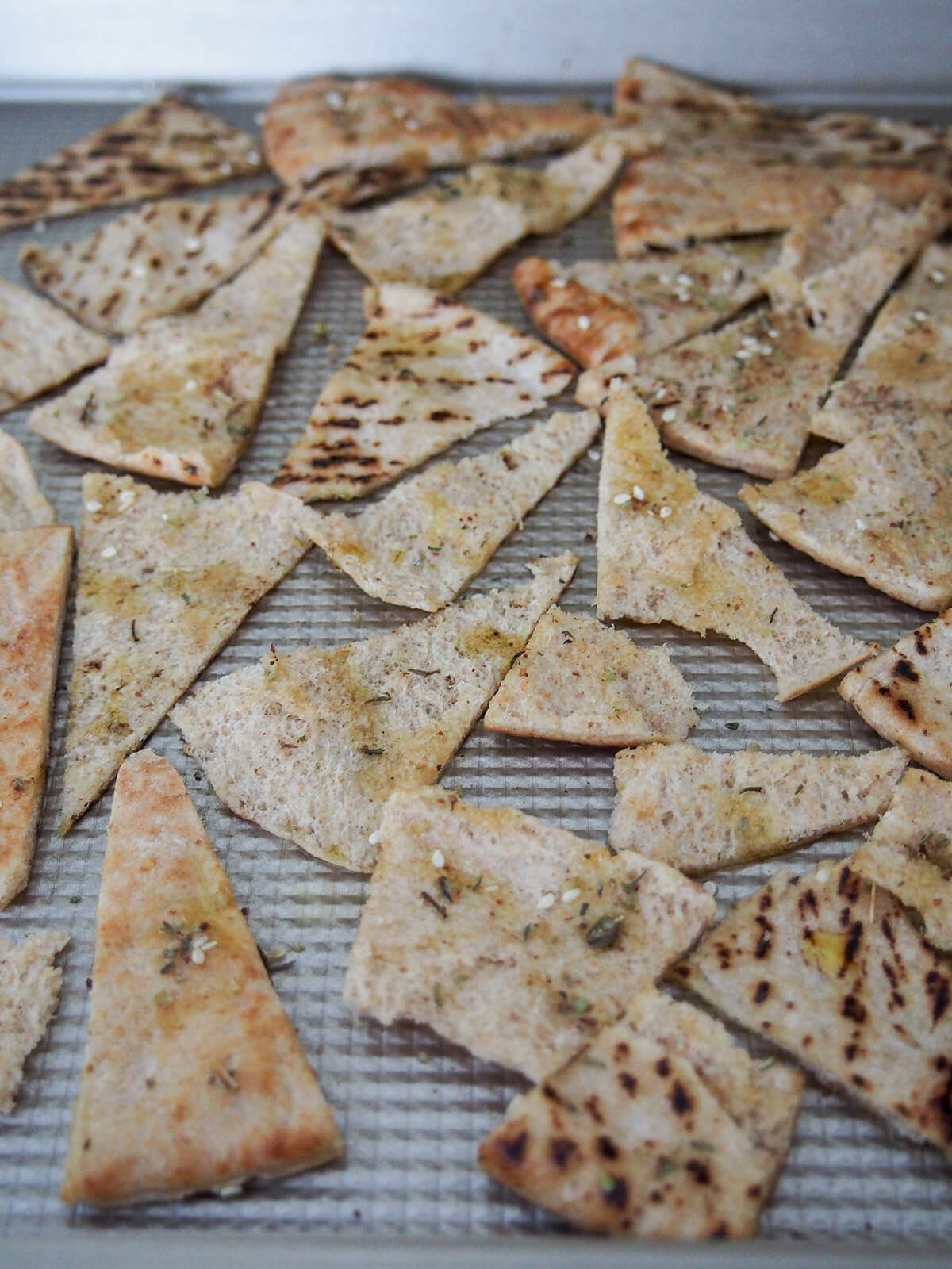pieces of pita bread on baking sheet with a little oil and za'atar on them