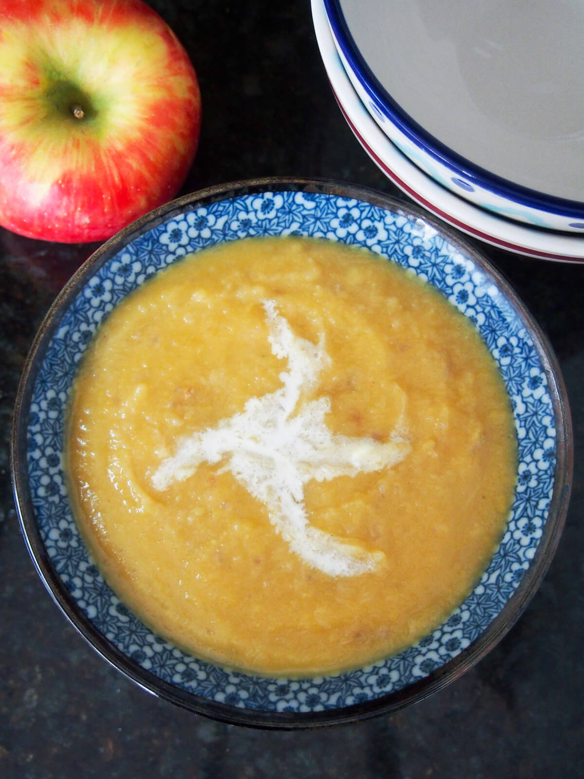 bowl of roasted apple and acorn squash soup from overhead with apple in corner