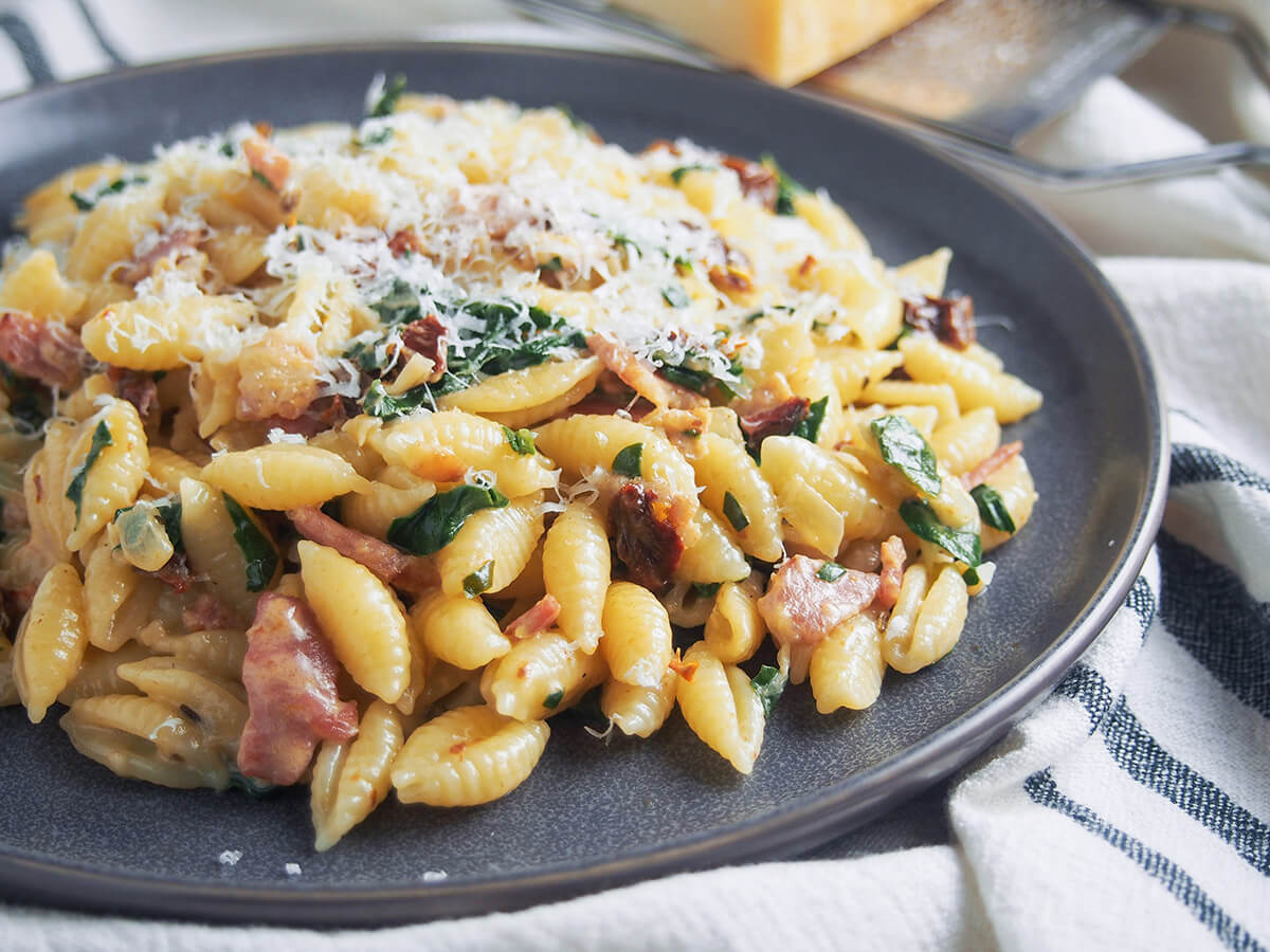 side view of plate of Bacon sun dried tomato pasta with spinach and cream
