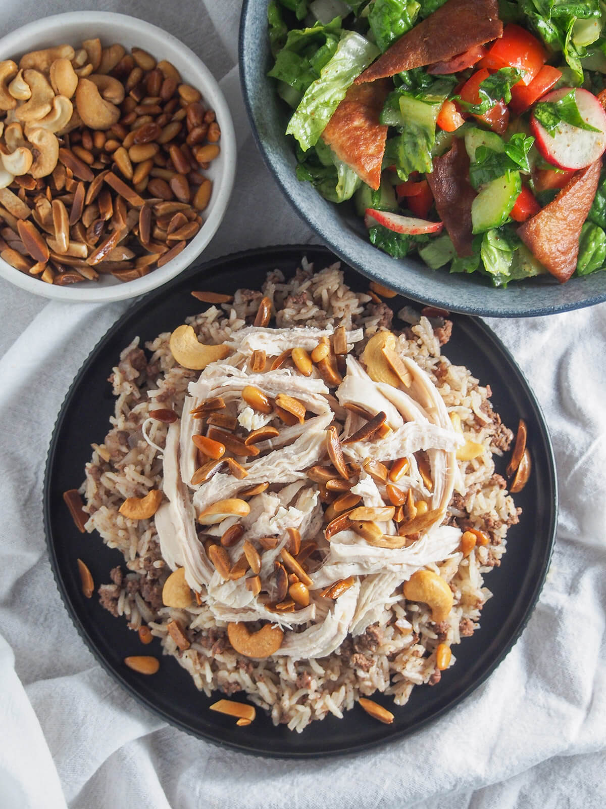 plates with Lebanese chicken and rice , fattoush salad and toasted nuts from overhead