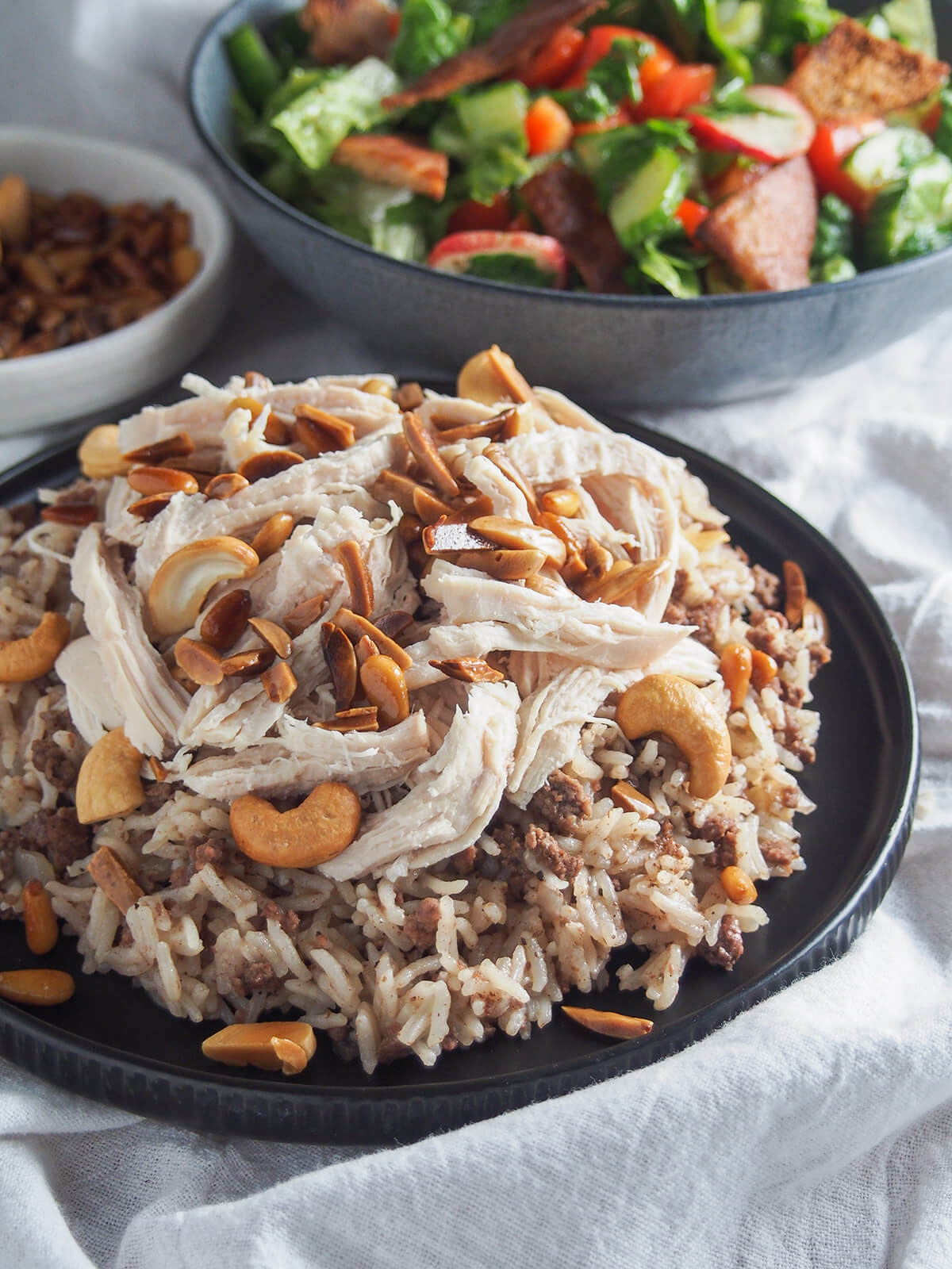 side view of Lebanese chicken and rice with fattoush salad behind