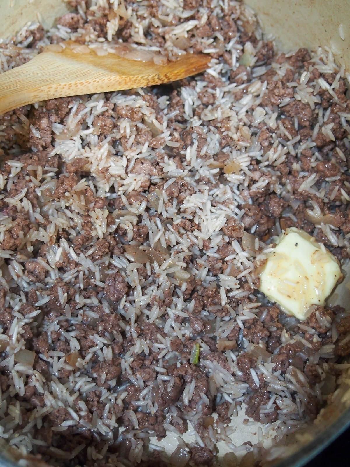adding rice and butter to pot with ground meat and onion