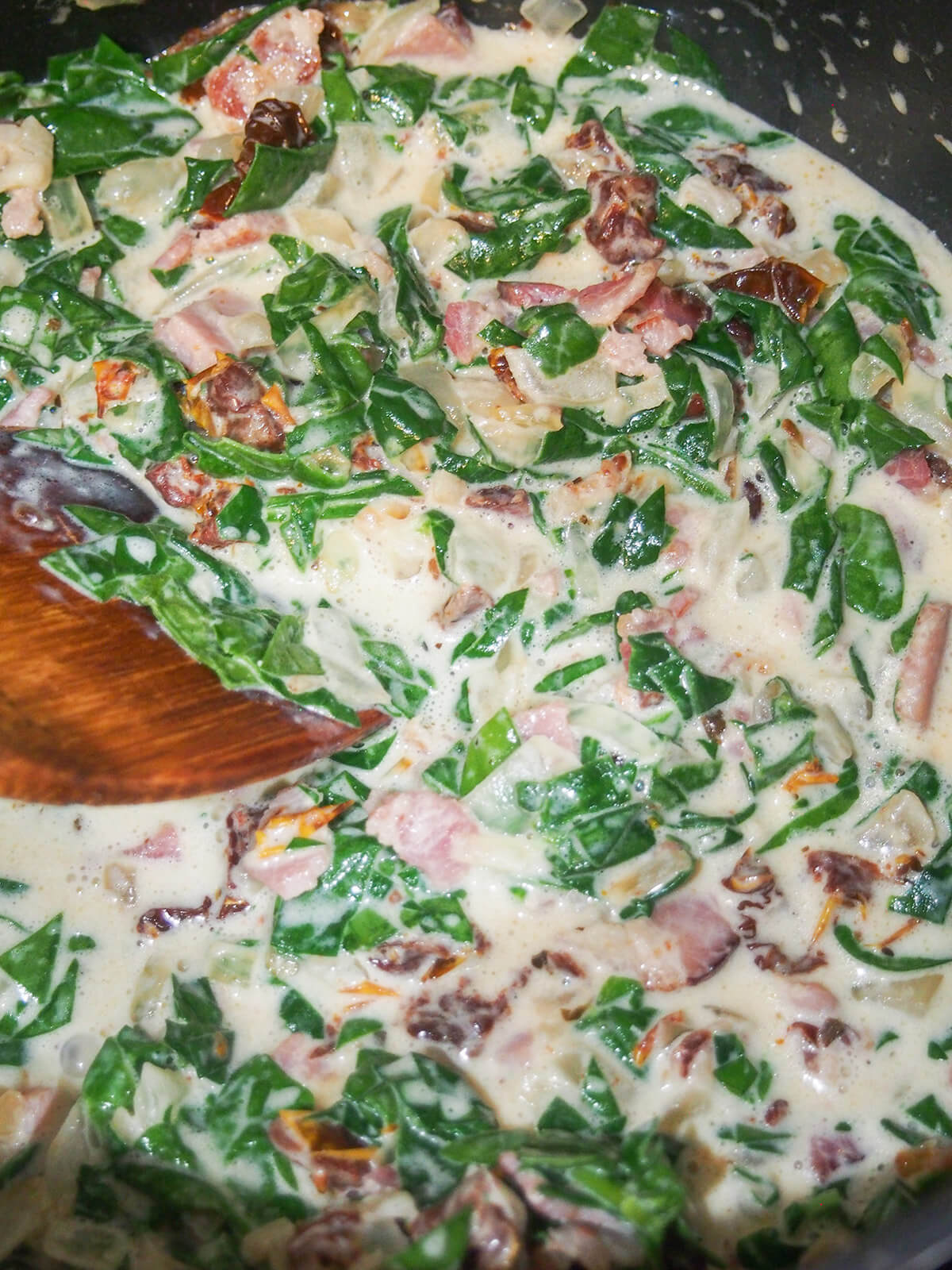 stirring creamy bacon sun dried tomato and spinach sauce