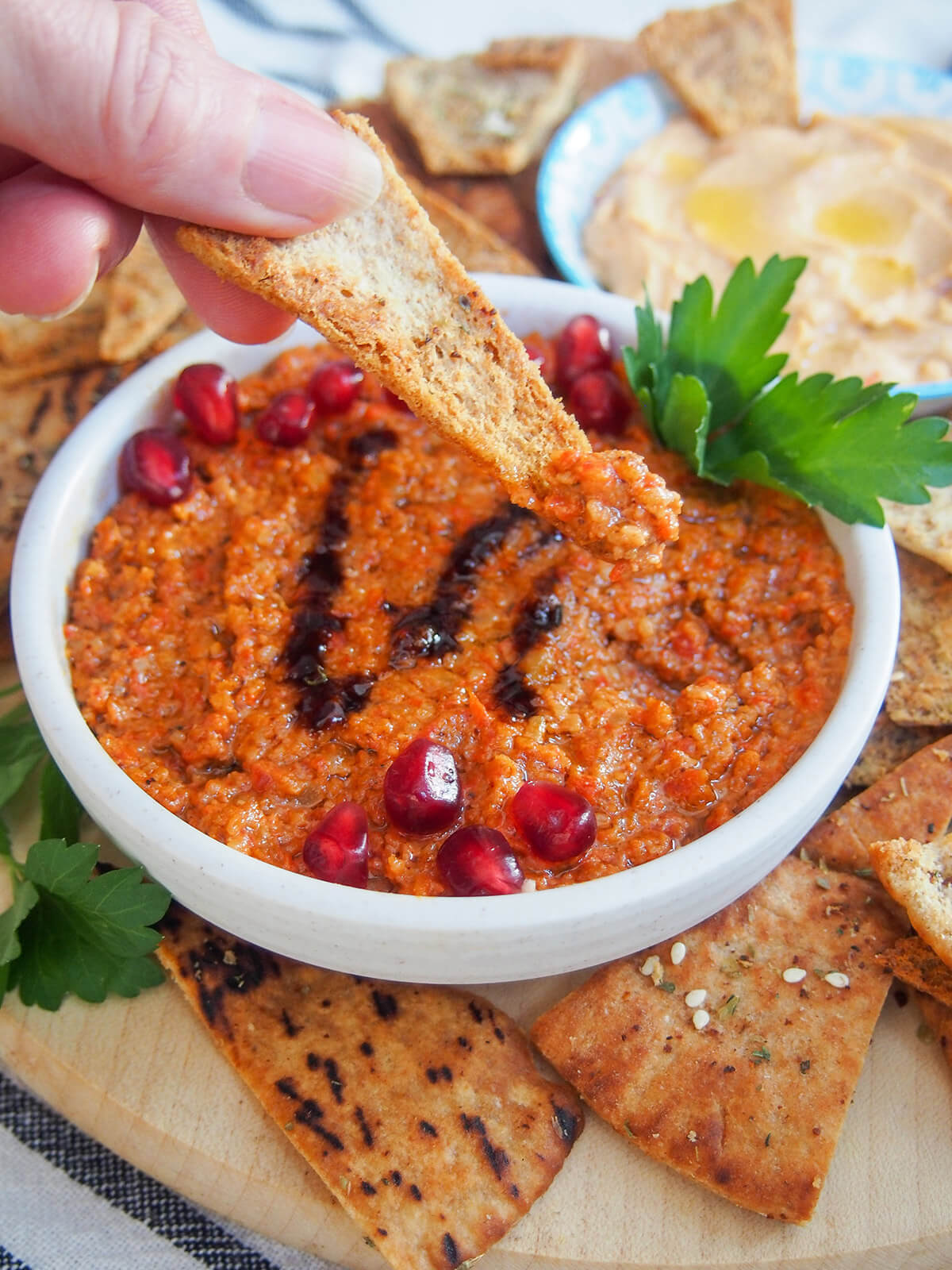 scooping some muhammara from dish with a pita chip
