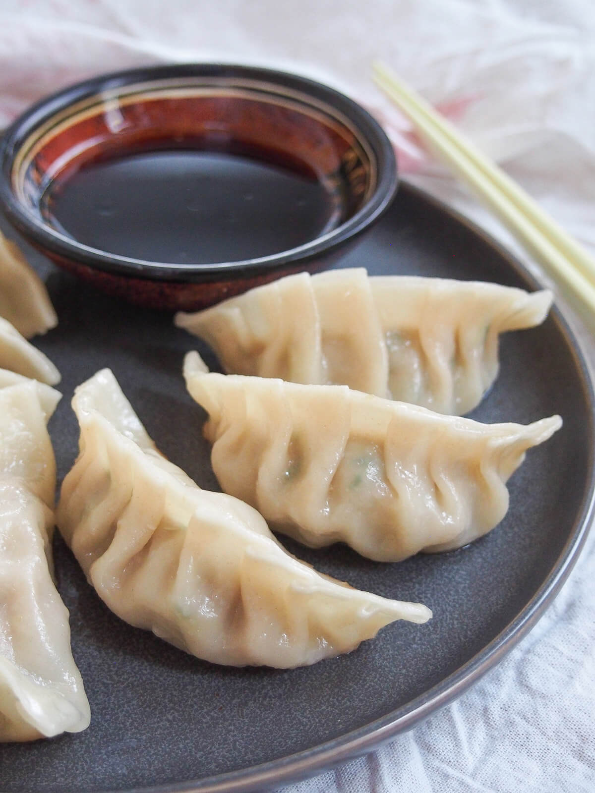 Pork and cabbage dumplings are a traditional dish, especially eaten for the Lunar New Year, but these dumplings are so delicious you'll want to have them more often! pork and cabbage dumplings on plate with dipping sauce behind
