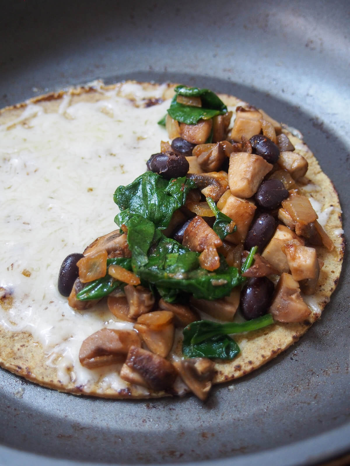 adding mushroom bean filling on top of cheese on tortilla