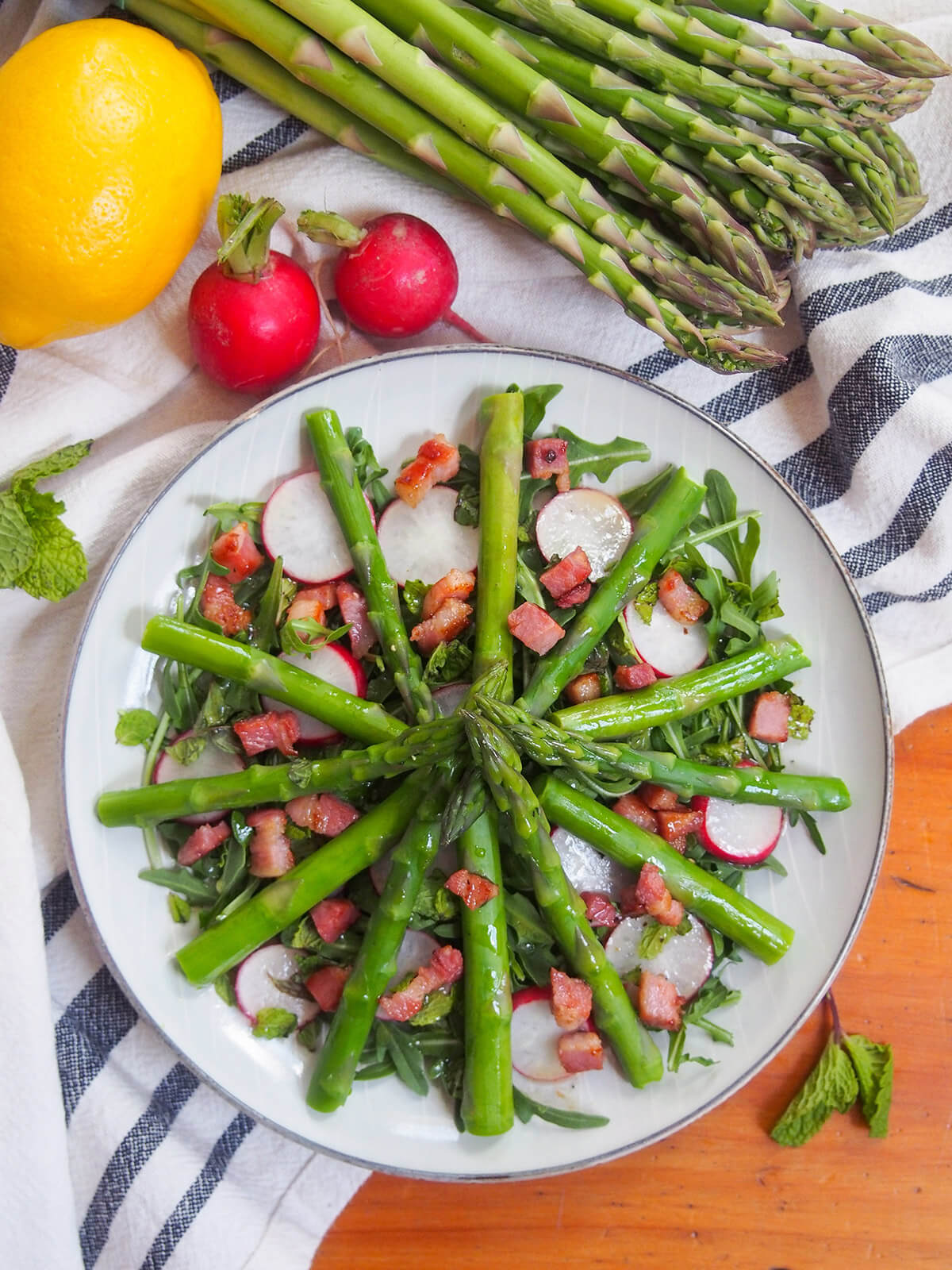 plate of asparagus salad from overhead with asparagus, radishes and lemon above plate