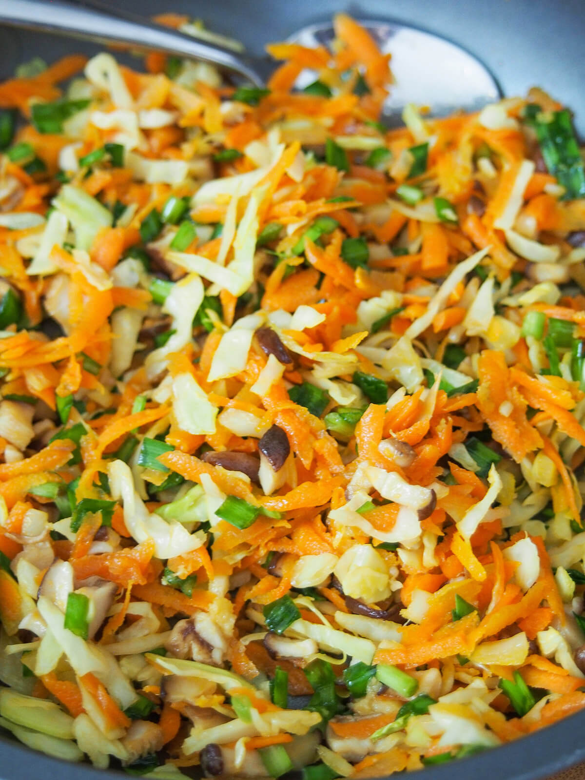 skillet with cooked shredded cabbage, carrot, mushroom and chives