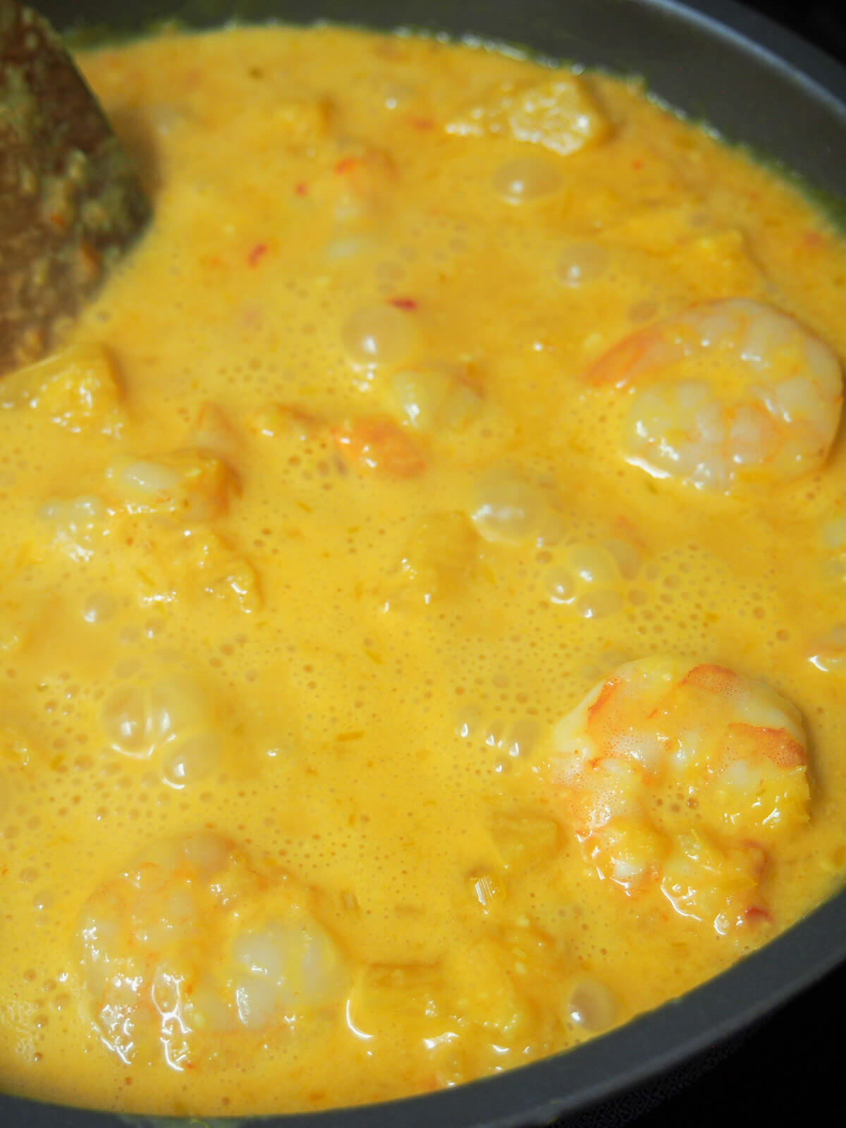 cooking pineapple shrimp curry in skillet