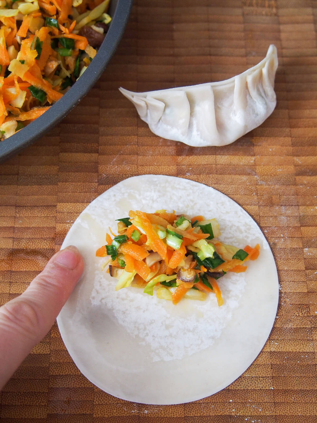 dampening edge of dumpling wrapper with some of vegetable filling on top