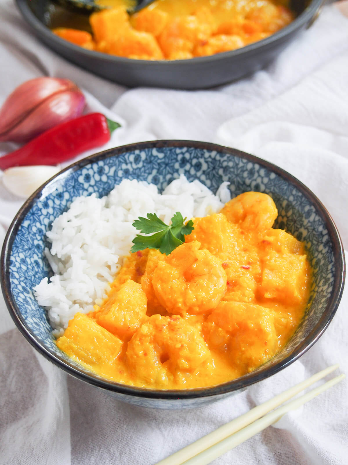 bowl of pineapple shrimp curry with pan with more behind