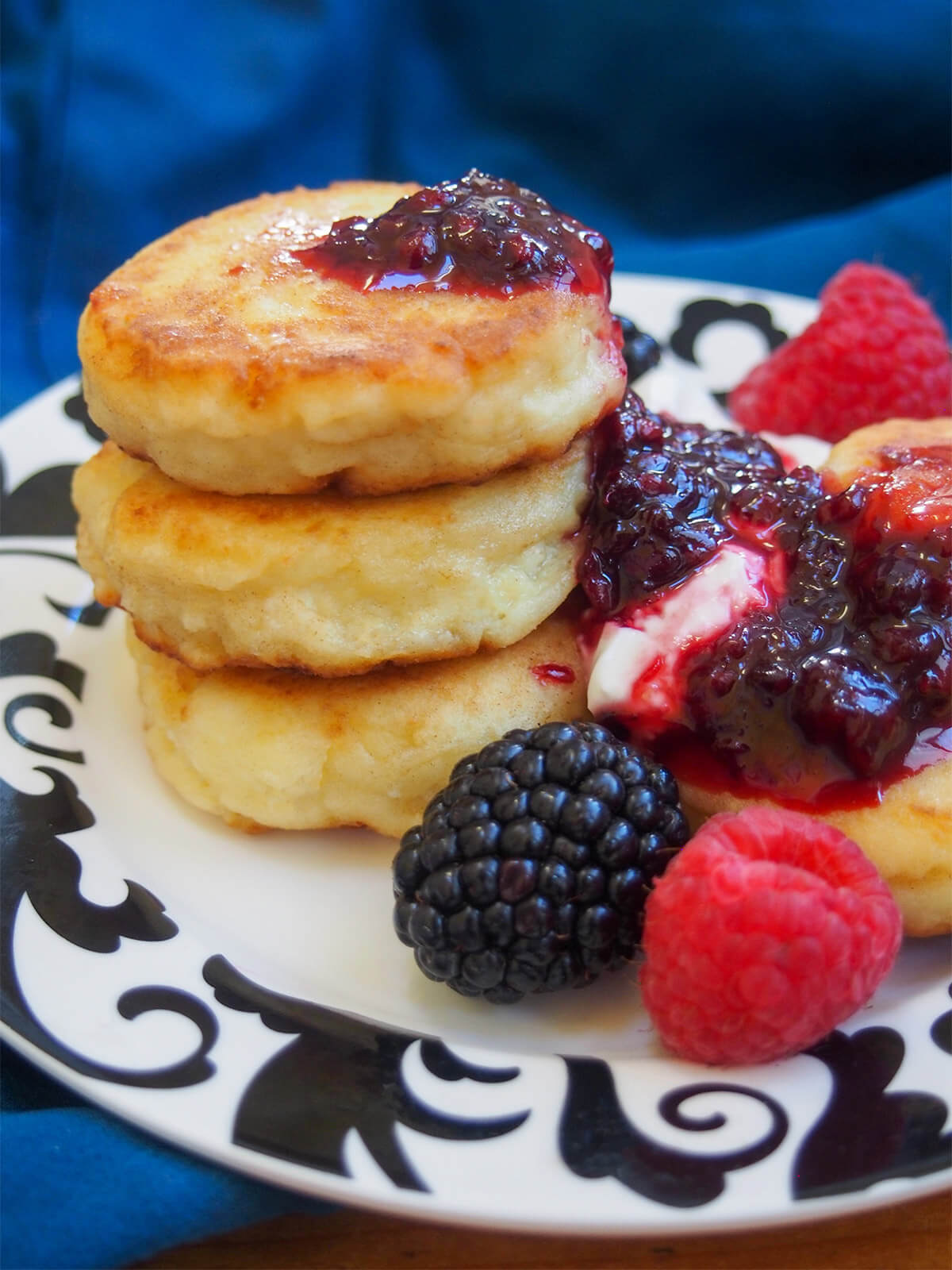 stack of syrniki Russian cheese pancakes with fruit and jam to side