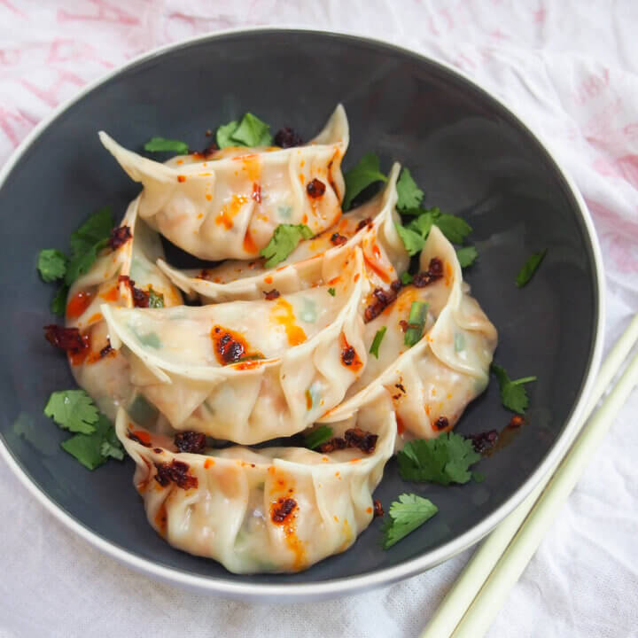 bowl of vegetable dumplings (jiaozi) topped with chili oil