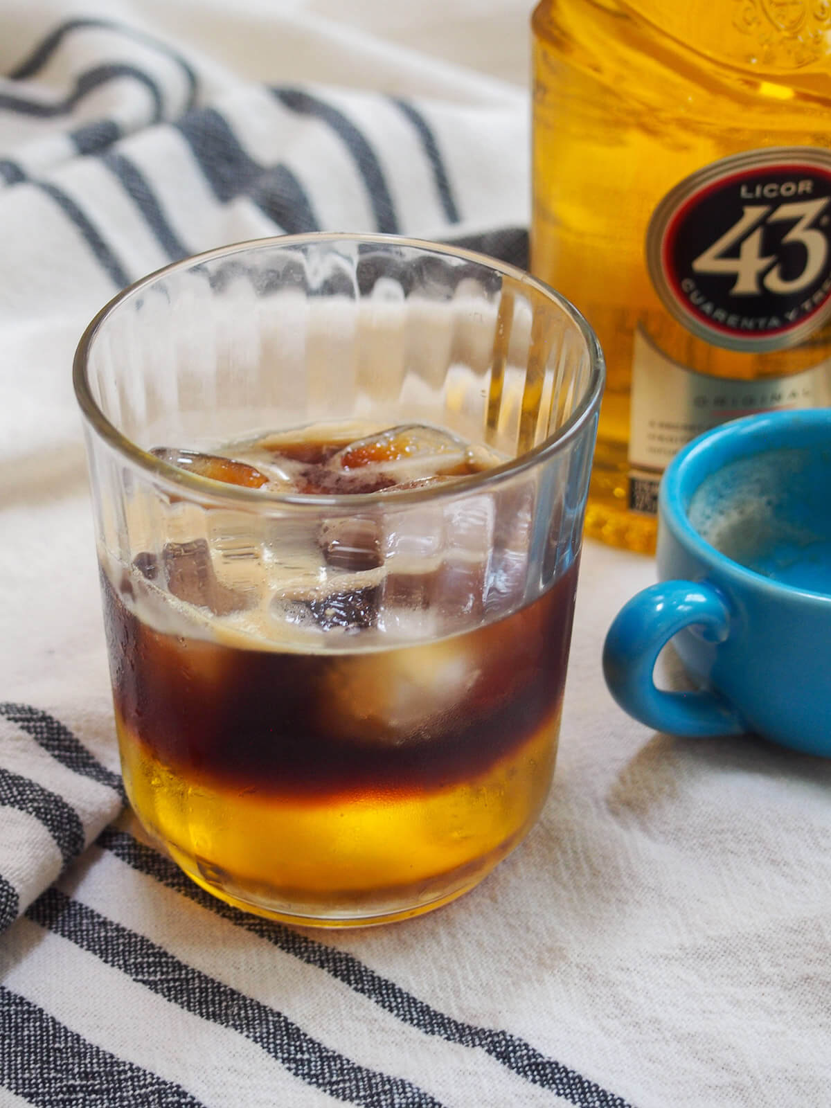 glass of Mexican carajillo coffee cocktail with empty espresso cup and bottle to side
