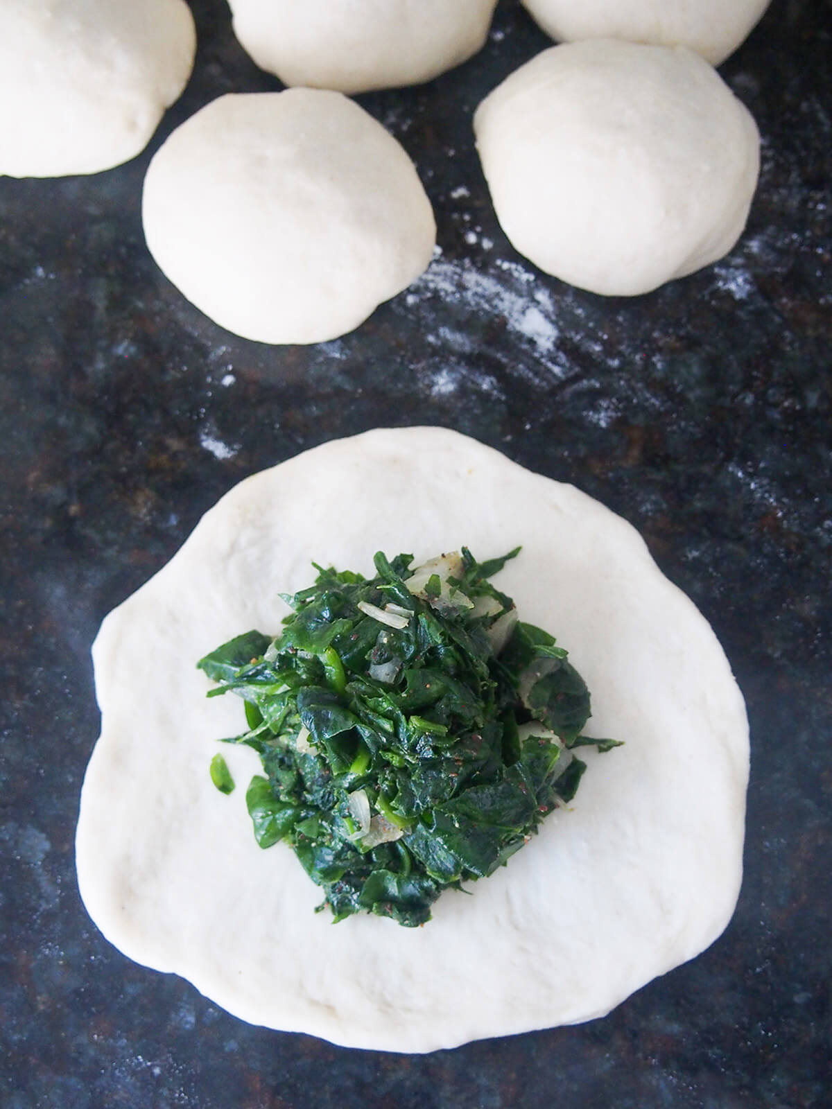 some spinach filling on top of a rolled out piece of dough