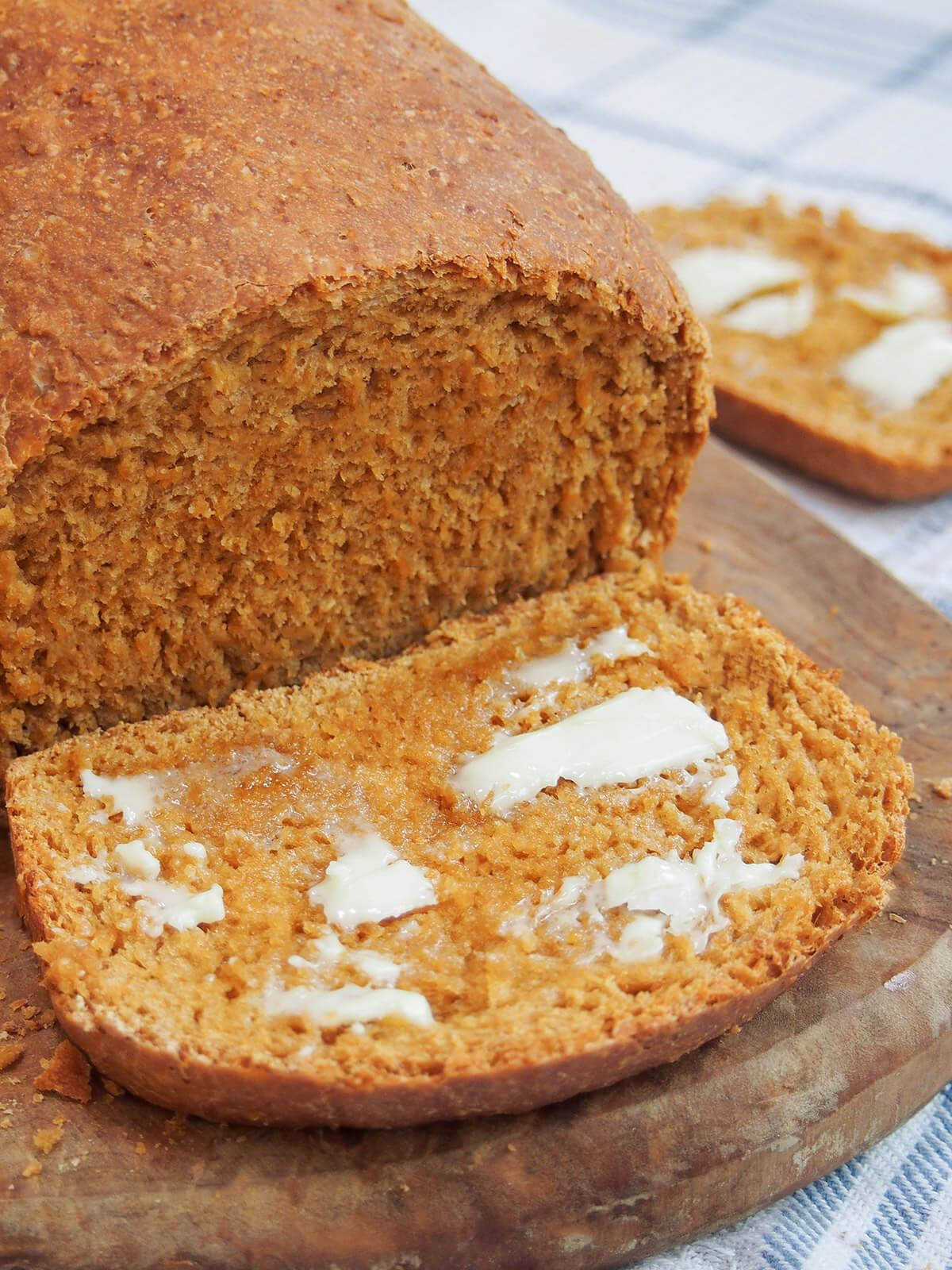 slice of anadama bread with butter on it in front of rest of loaf