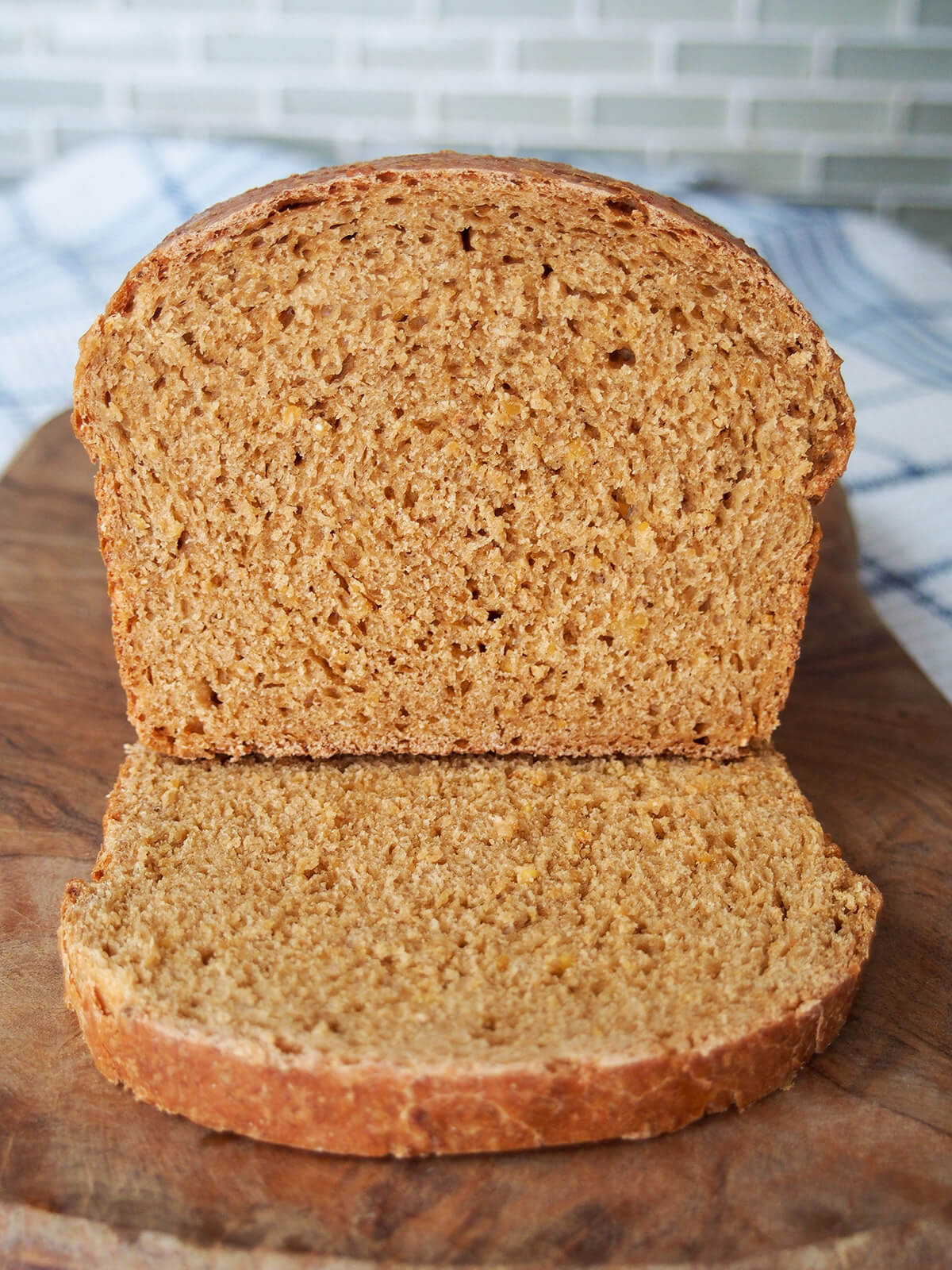 part of loaf of anadama bread resting on a slice on wooden board