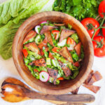 bowl of fattoush salad from overhead with serving spoons below