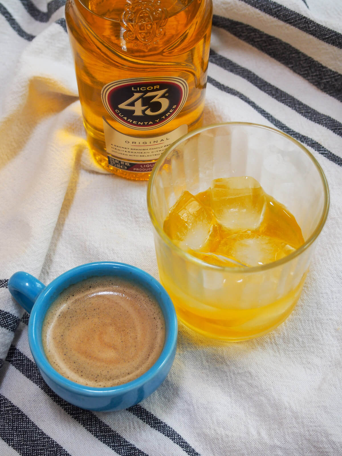 glass of licor 43 with cup of espresso to side and bottle behind