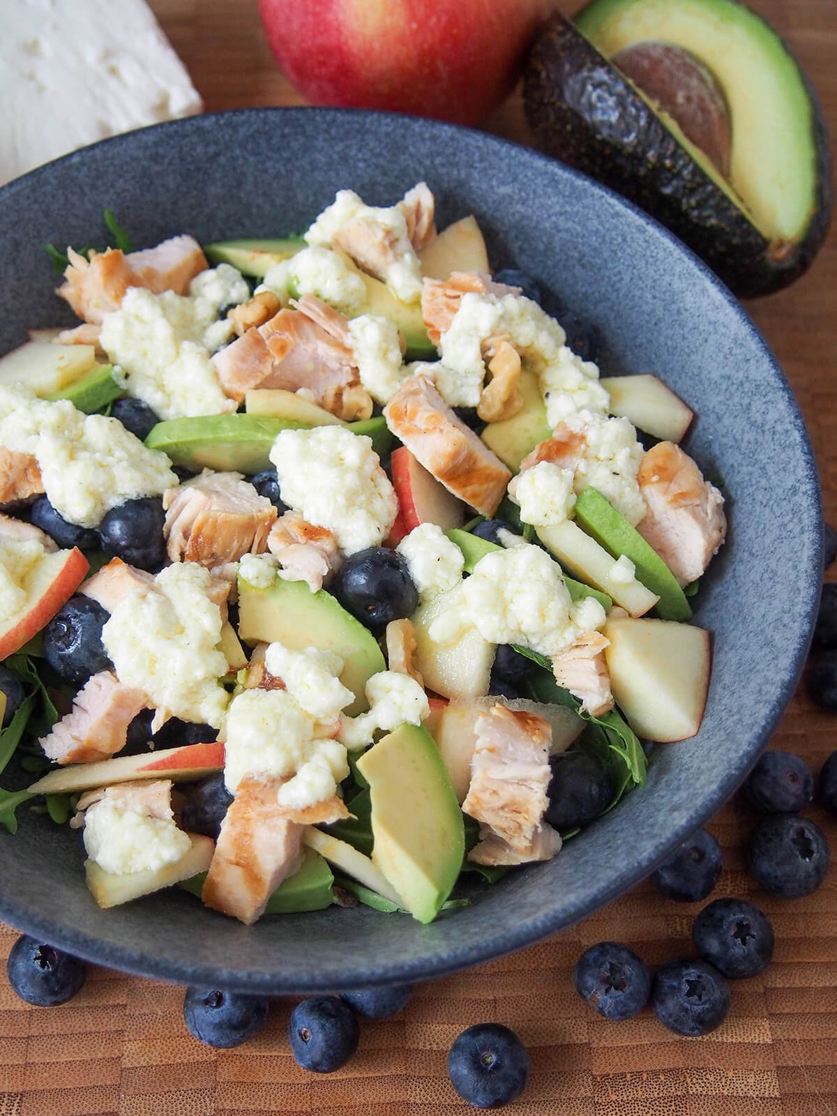 side view of bowl of grilled chicken blueberry salad with blueberries below bowl