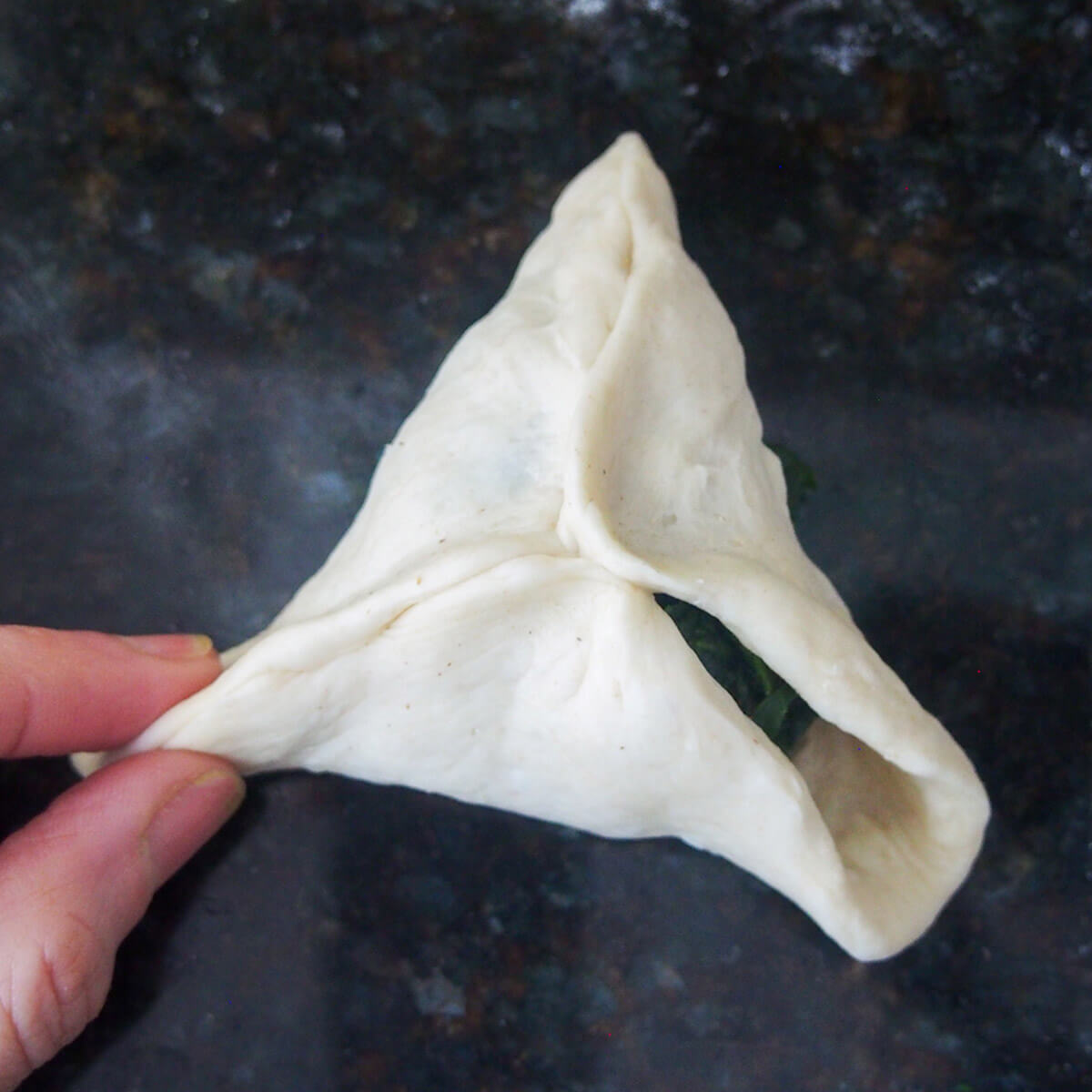 pinching together dough to form triangle shaped pastry