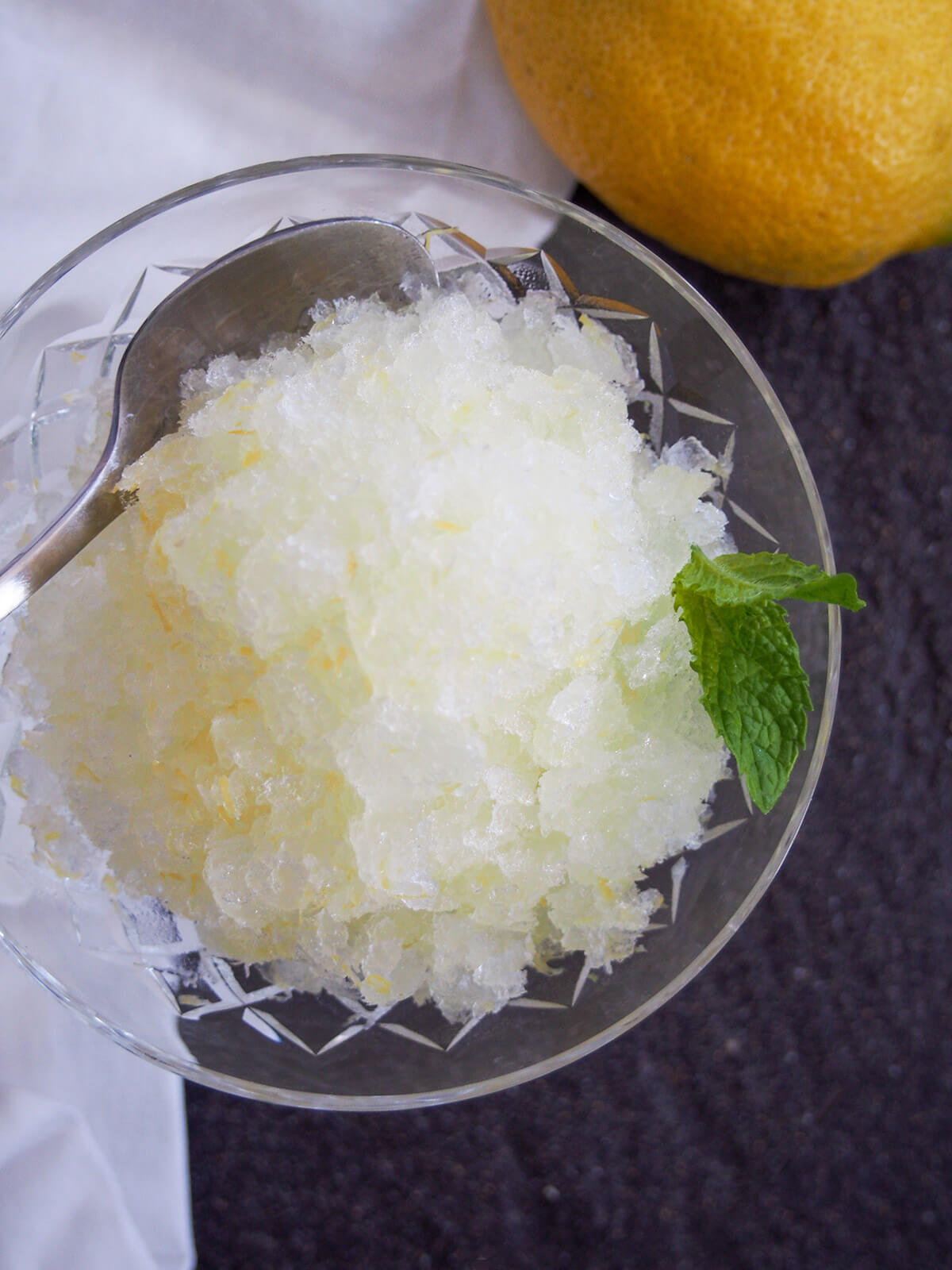 overhead view of glass of lemon granita with spoon in side