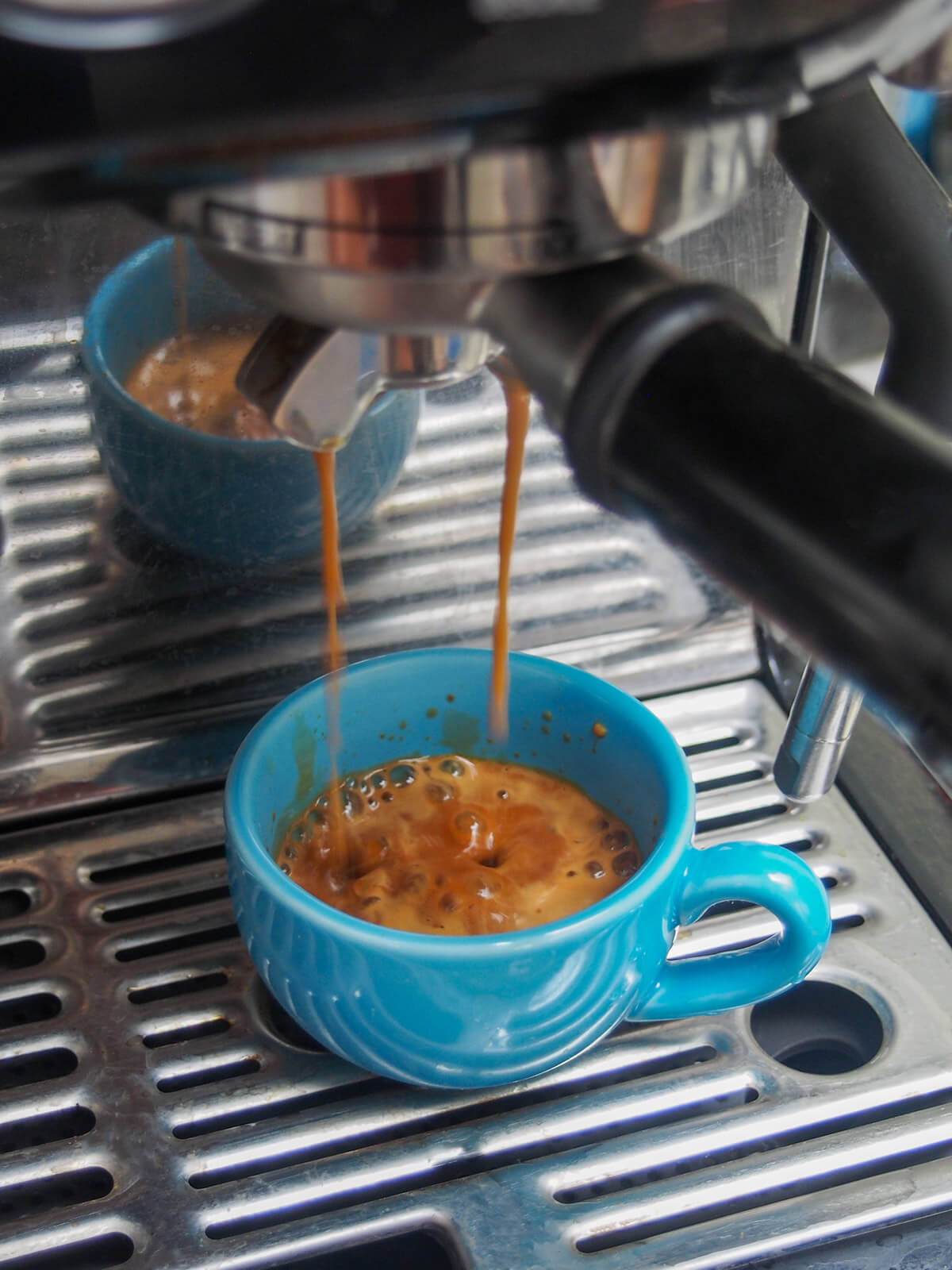 making espresso with turquoise cup of coffee below