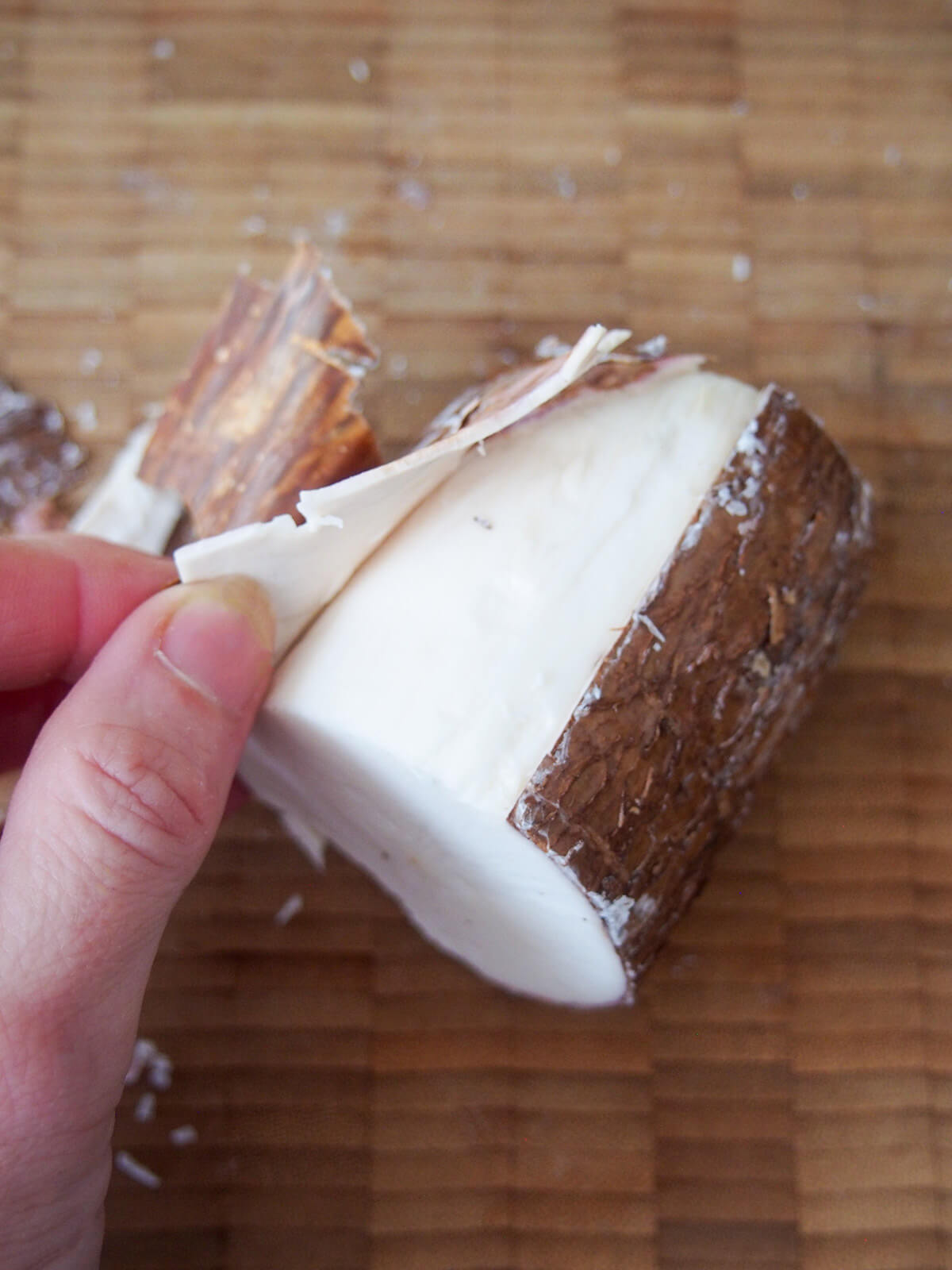 peeling skin from a piece of yuca