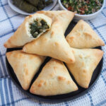 plate of spinach fatayer with one bitten into on top