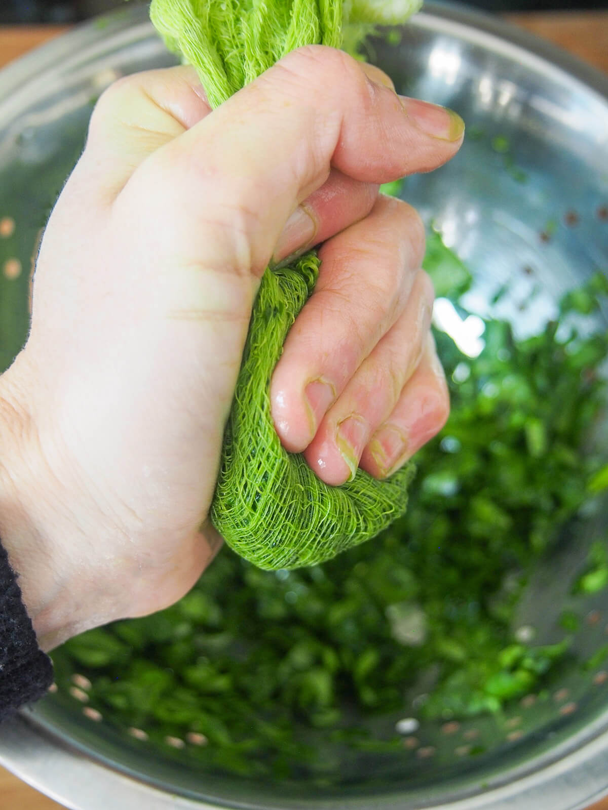 holding spinach in cheesecloth to squeeze out liquid