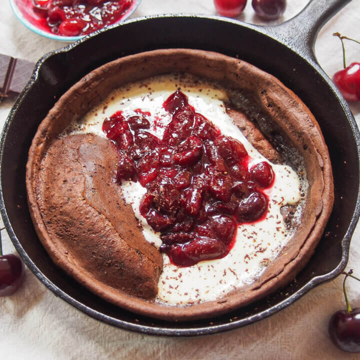 close view of chocolate Dutch baby pancake with cherry compote